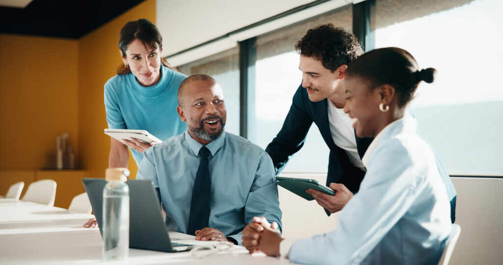 Professionnels échangeant sur un projet avec une tablette et un ordinateur