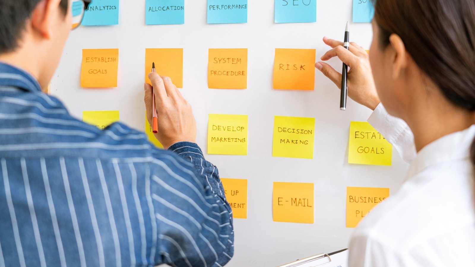 Deux collègues définissant leur plan d’action sur des notes adhésives